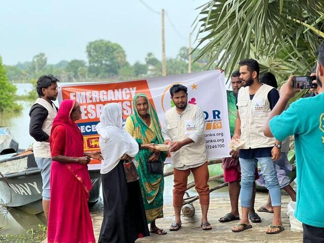 NHDR volunteers distributing food beside floodwaters