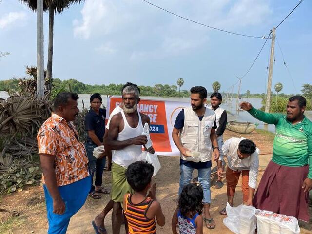 An NHDR volunteer handing a meal box to a man during flood relief